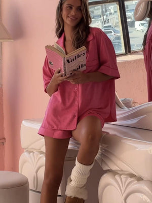 a woman in a pink shirt dress is reading a book