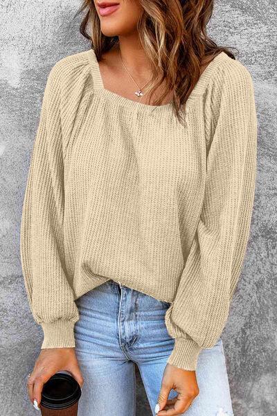 a woman wearing a beige sweater and ripped jeans