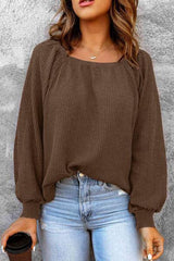 a woman wearing a brown sweater and jeans