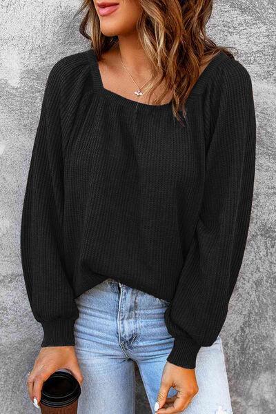 a woman wearing a black sweater and ripped jeans