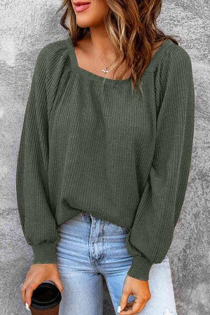 a woman wearing a green sweater and ripped jeans