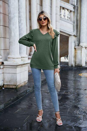 a woman wearing a green sweater and jeans