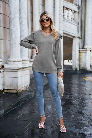 a woman standing in the rain wearing a sweater and jeans