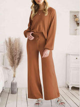 a woman standing in a room wearing a brown jumpsuit