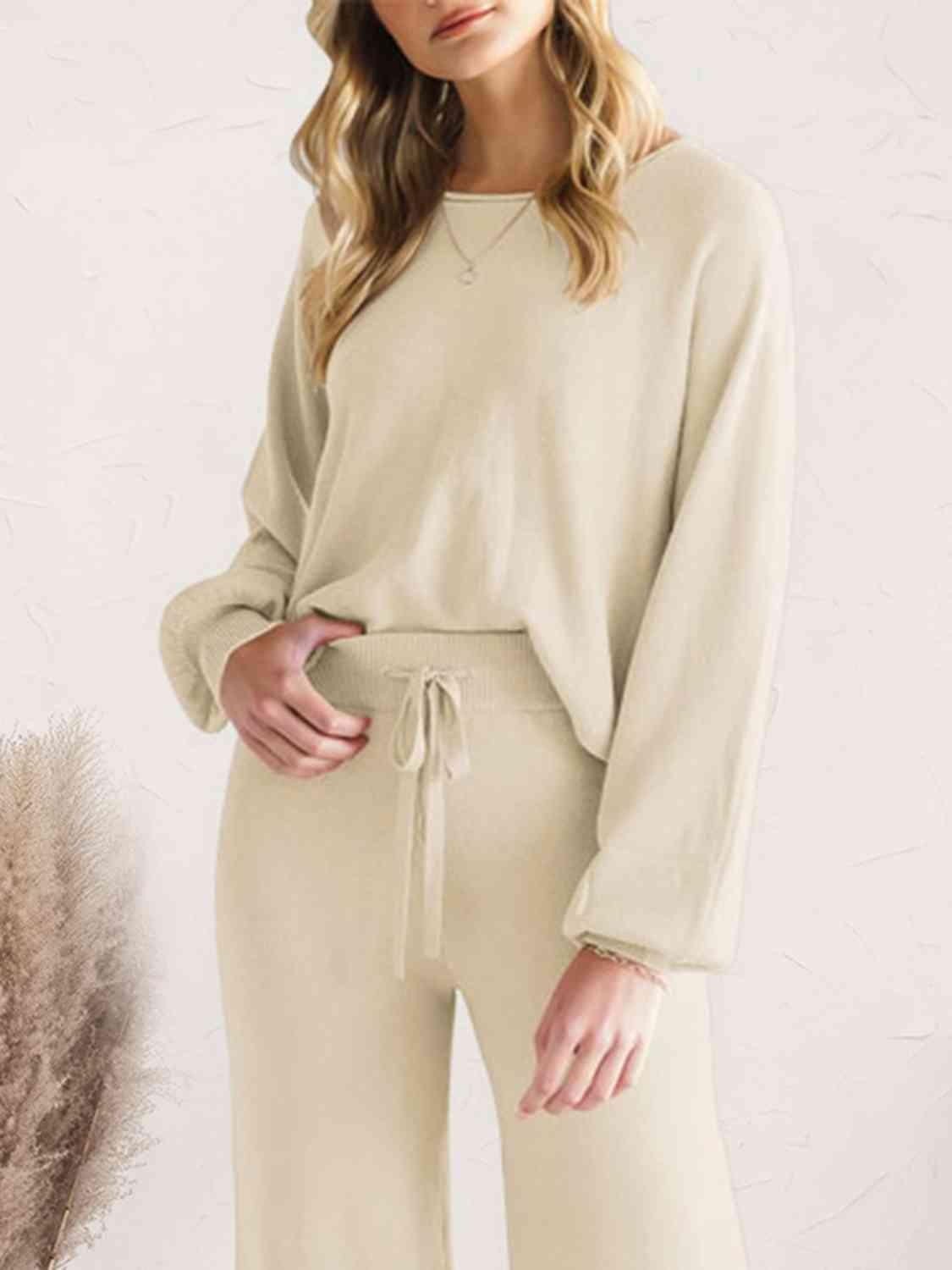 a woman wearing a beige sweater and wide legged pants