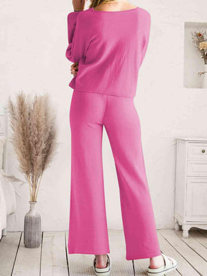 a woman in a pink top and wide legged pants