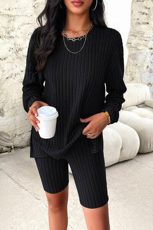 a woman in a black sweater and shorts holding a cup of coffee