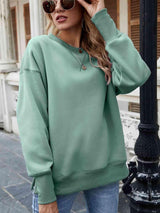 a woman wearing a green sweatshirt and jeans