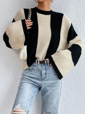 a woman wearing ripped jeans and a black and white sweater