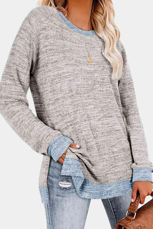 a woman wearing a grey sweater and ripped jeans