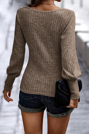 a woman walking down a street wearing a brown sweater