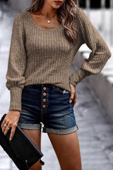 a woman wearing a tan sweater and denim shorts