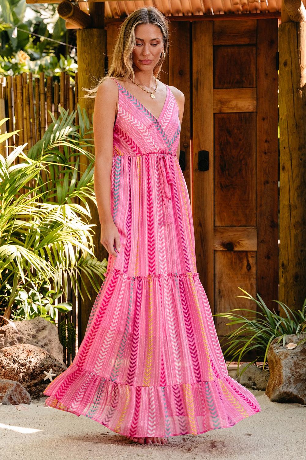 a woman in a pink dress standing in front of a wooden structure