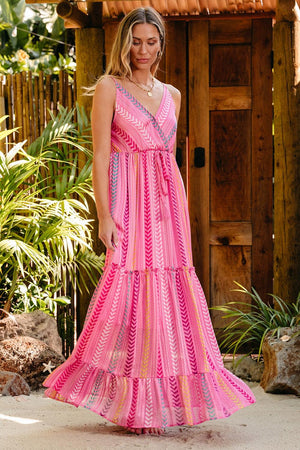 a woman in a pink dress standing in front of a wooden structure