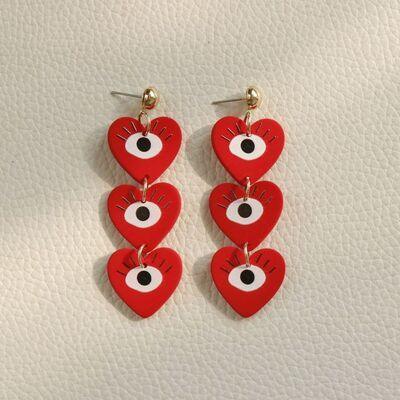 a pair of red heart shaped earrings with eyeballs