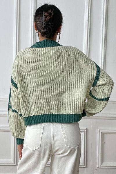 a woman wearing a green sweater and white pants