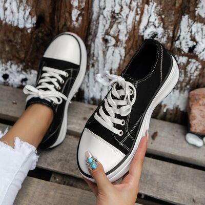 a woman's hand holding a black and white shoe