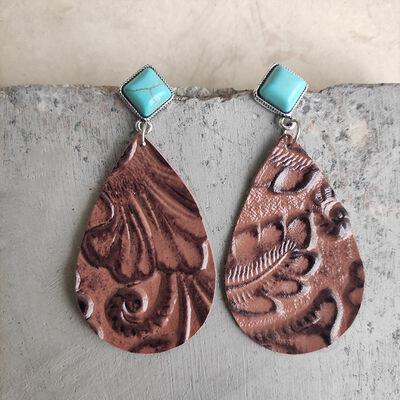 a pair of brown and turquoise earrings on a rock