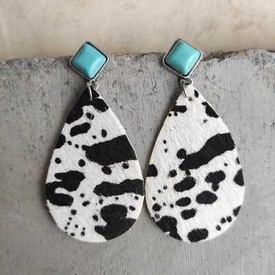 a pair of black and white earrings with turquoise accents