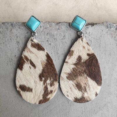 a pair of brown and white cow print earrings