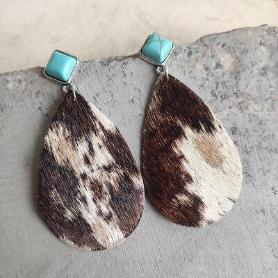 a pair of brown and white cowhide earrings