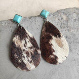 a pair of brown and white cowhide earrings