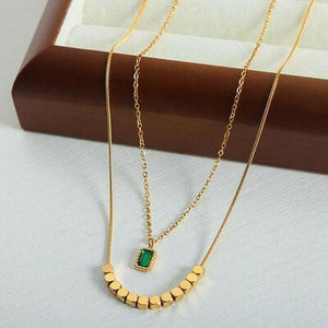 a gold necklace with a green stone on it