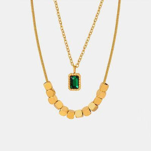 a gold necklace with a green stone on it