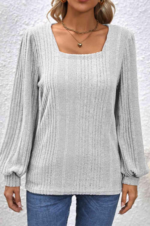 a woman wearing a gray sweater and jeans