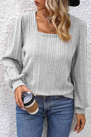 a woman wearing a gray sweater and jeans