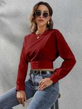 a woman sitting on a stool wearing a red top