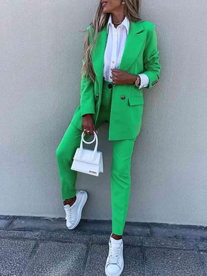 a woman in a green suit leaning against a wall