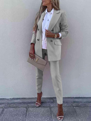 a woman standing against a wall wearing a blazer and pants