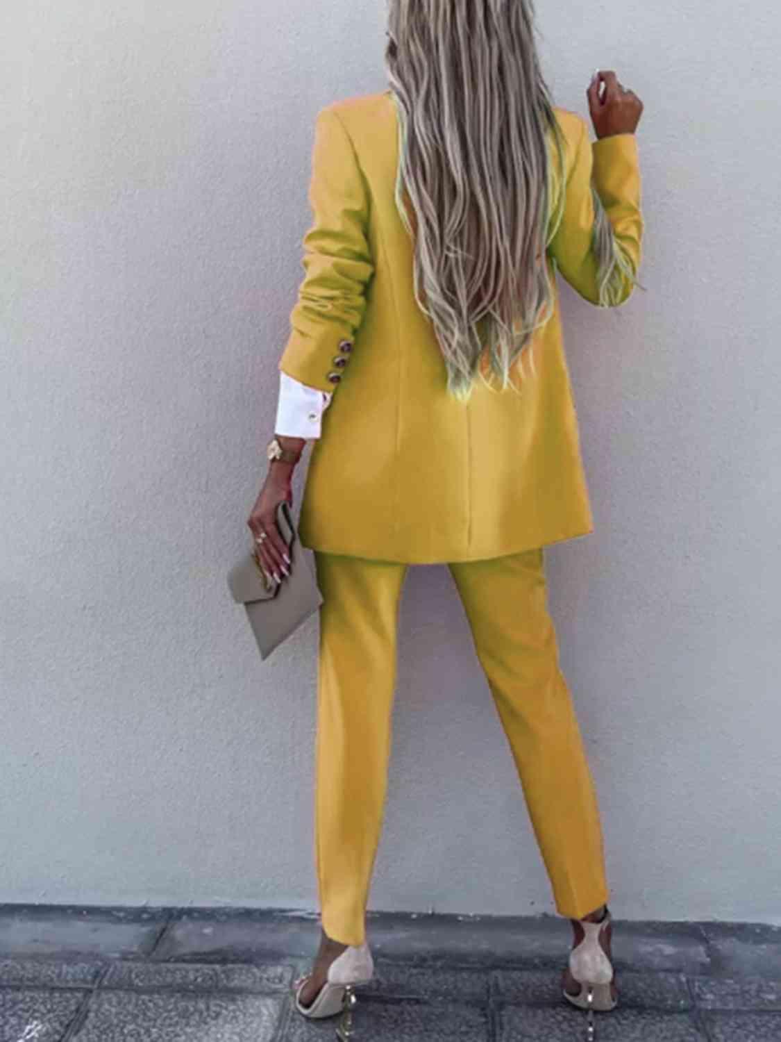 a woman in a yellow suit standing against a wall
