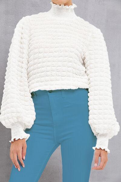 a woman wearing a white sweater and blue pants