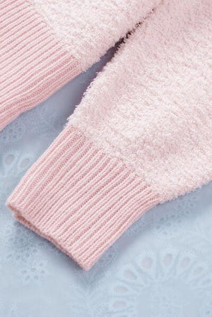 a close up of a pink sweater on a blue surface