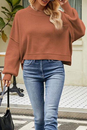 a woman wearing a brown sweater and jeans