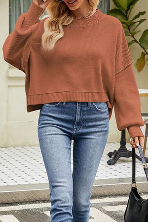 a woman wearing a brown sweater and jeans