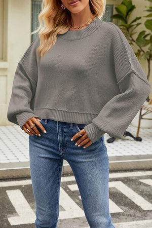 a woman wearing a grey sweater and jeans