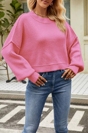 a woman wearing a pink sweater and jeans