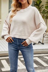 a woman standing on the street wearing a sweater and jeans