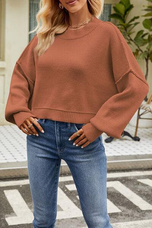 a woman wearing a brown sweater and jeans