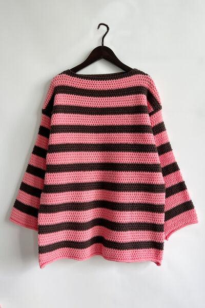 a pink and black striped sweater hanging on a hanger