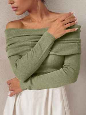 a woman wearing a green sweater and white skirt