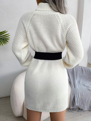 a woman wearing a white sweater dress with a black belt