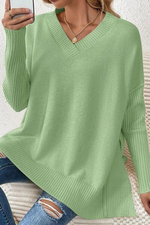 a woman wearing a green sweater and ripped jeans