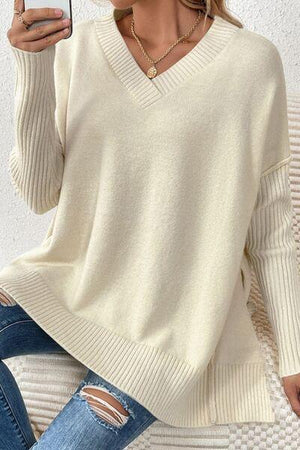 a woman wearing a white sweater and ripped jeans