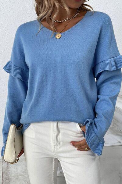 a woman wearing a blue sweater and white pants