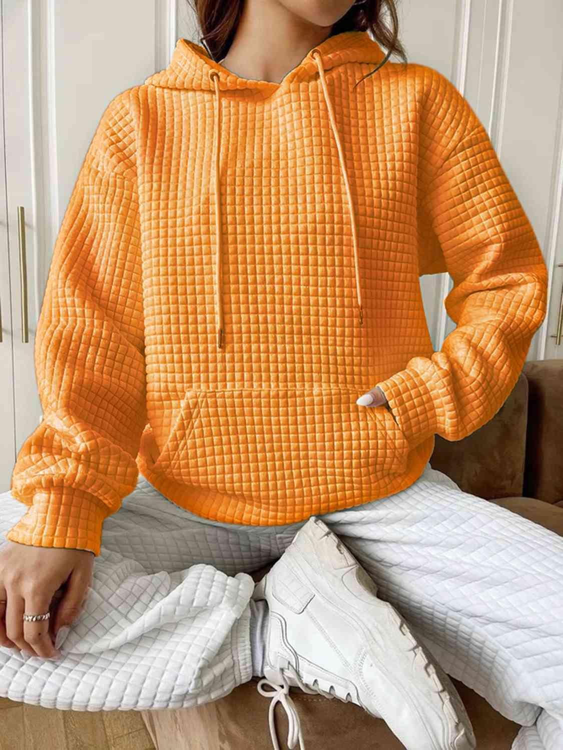 a woman sitting on a couch wearing an orange hoodie