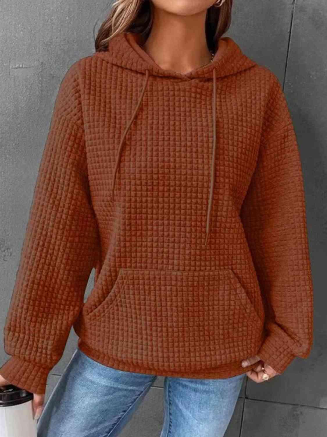 a woman wearing a brown sweater and jeans